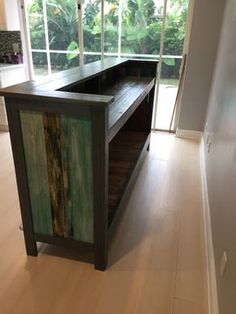 a kitchen island made out of wood and painted with green paint on the top, in front of a large window