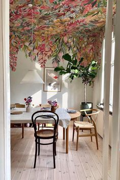 a dining room filled with lots of furniture and flowers hanging from the ceiling above it