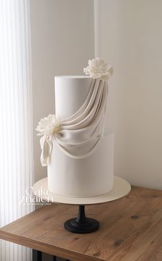 there is a white cake with flowers on the top and bottom, sitting on a wooden table