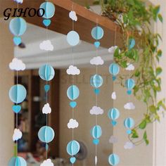 a blue and white cloud mobile hanging from a wooden frame in front of a mirror