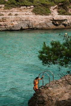 a man standing on top of a cliff next to a body of water