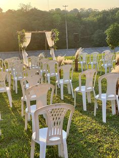 rows of white plastic chairs set up in the grass for an outdoor wedding ceremony at sunset