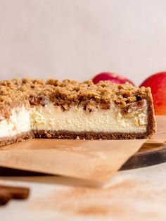 a piece of cheesecake sitting on top of a cutting board next to an apple