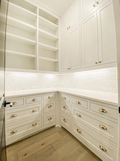 an empty pantry with white cabinets and wood flooring in a home office area,