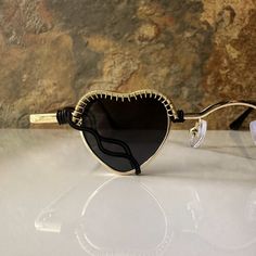 These heart sunglasses are wrapped with black and gold wire.Comes with a cleaning cloth and a pouch to store the sunglasses in. All orders include freebie crystals and stickers. Chic Black Metal Sunglasses, Trendy Black Heart-shaped Sunglasses, Black Glass Sunglasses For Festival, Black Sunglasses With Tinted Lenses As Gift, Black Sunglasses With Tinted Lenses For Gift, Chic Sunglasses With Tinted Lenses, Black Sunglasses With Tinted Lenses, Black Tinted Sunglasses As A Gift, Valentine's Day Gift Sunglasses With Tinted Lenses