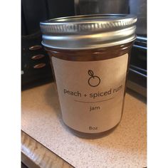 a jar of jam sitting on top of a counter next to an oven with the label peach spiced rum