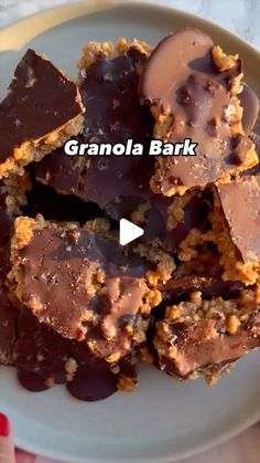 a plate full of granola bark on top of a white plate with chocolate and nuts