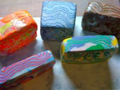 four different colored soaps sitting on top of a counter next to each other in front of a window