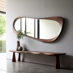 a wooden bench sitting next to a large mirror on the side of a white wall