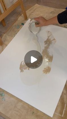 a person is painting an apple logo on a piece of white paper with gold foil