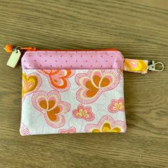 a small pink and orange flowered pouch on a wooden table