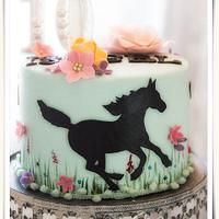 there is a cake decorated with a horse and flowers on the bottom layer, along with other decorations