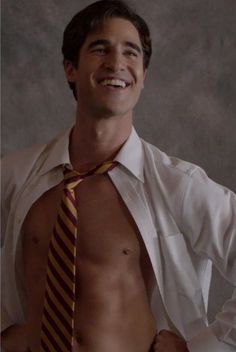 a shirtless man wearing a striped tie and white dress shirt is smiling at the camera