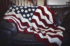 an american flag crocheted afghan is draped on a leather couch in the living room