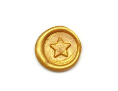 a gold colored button with a star on the front and bottom, sitting on a white surface