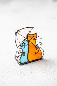 an orange and blue cat sitting on top of a white floor next to a umbrella