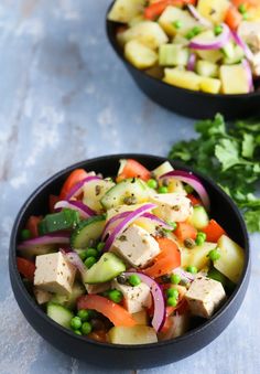 two black bowls filled with vegetables and tofu