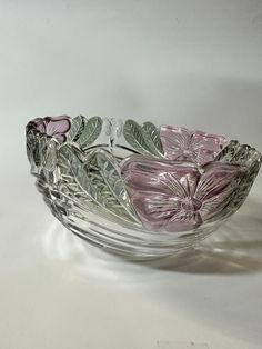 a glass bowl with flowers and leaves on it