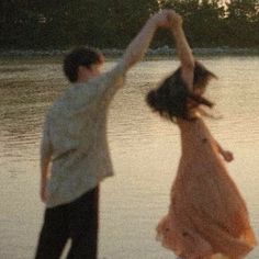 two people standing on the beach with their arms in the air