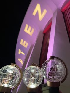 three glass globes with lights on them in front of a neon sign