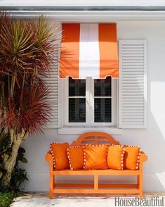 an orange and white striped awning next to a wooden bench with pillows on it