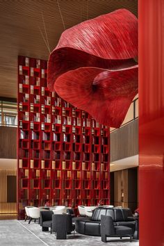 a large red sculpture hanging from the side of a building next to couches and tables