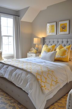 a bed with yellow and white pillows in a bedroom next to two lamps on either side of the bed