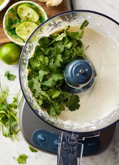 a food processor with cilantro and limes in it next to other ingredients