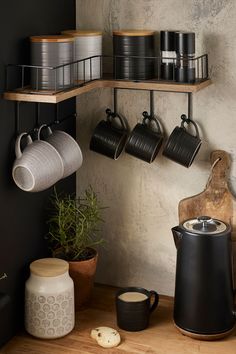 pots and pans are hanging on the wall next to a pot rack with coffee mugs