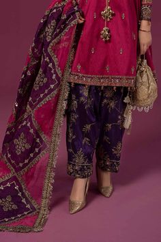 Maria B Raw Silk Salwar Kameez Pakistani Party Dress is a traditional attire that will give you a stunning look on the festive occasion. The kameez is beautifully embellished with tilla, sequins, embroidery, and pearls. Embellished borders and neckline give a perfect finishing to the kameez. The Salwar has an alluring purple shade that gives a lavish contrast to the attire. An embellished organza dupatta completes the overall look of this Pakistani Party Wear. Detailed Description: SKU: PS2406 Detailing: Embroidery, Motifs, Sequins, Pearls, Cutwork, Crystals, Stones, Tilla Color: Pink, Purple Fabric: Organza, Raw silk Design: Fully Embellished Dress with Embroidery, Tilla Event: Bridal wear, Wedding Brinjal Colour Combination Dress, Dark Purple Pakistani Dress, Mendhi Dresses, Raw Silk Salwar, Fabric Study, Frock Suit, Salwar Kameez Pakistani, Combination Dresses, Silk Design