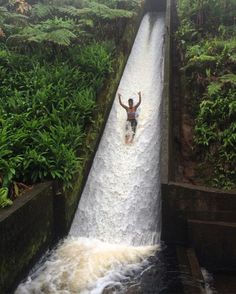 a man riding a water slide down a waterfall