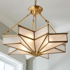 a chandelier hanging from the ceiling in a room with white walls and windows