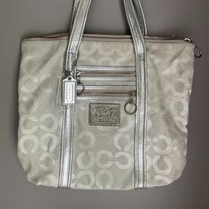 Coach Signature Poppy Tote. Gently Used, Like New. The Silver And Pink Interior Makes This A Beautifully Unique Bag For Spring And Summer. Zip Top Closure Canvas And Leather Shoulder Straps Zipper Pockets On Outside Front Silver Hardware Coach Hangtag Interior Zipper Pocket With Authenticity Patch & 2 Slip Pockets Key Ring Approx Measurements: 14" Length 4" Wide 12" Height 9" Strap Drop Coach Poppy, Bags Coach, Pink Interior, Unique Bags, Zip Top, Michael Kors Monogram, Silver Hardware, Womens Tote Bags, Key Rings