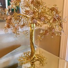 a glass table topped with a gold vase filled with flowers