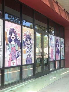 there are many anime posters on the windows of this store front window, which is decorated with cartoon characters