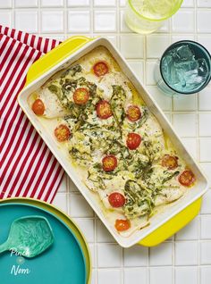 a pan filled with food on top of a white tiled counter next to plates and glasses