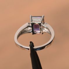 It is a natural amethyst ring. The main stone is 7 mm* 9 mm emerald cut.weight about 2.21 carats. The basic metal is sterling silver and plated with rhodium. To change the metal to a solid gold (white/rose) or platinum is also available, please ask for a quotation if you want. You can also go to my shop Home for more elegant rings: https://www.etsy.com/shop/godjewelry?ref=hdr_shop_menu Amethyst is February birthstone More amethyst rings: https://www.etsy.com/shop/godjewelry?ref=seller-platform-m Elegant Purple Amethyst Baguette Cut Ring, Emerald Cut Amethyst Ring For Formal Occasions, Elegant Purple Baguette Cut Amethyst Ring, Elegant Emerald Cut Amethyst Promise Ring, Elegant Emerald Cut Amethyst Ring, Purple Topaz Ring In Prong Setting, Fine Jewelry Purple Topaz Ring With Prong Setting, Purple Topaz Ring With Prong Setting, Purple Gemstone Rings With Baguette Cut