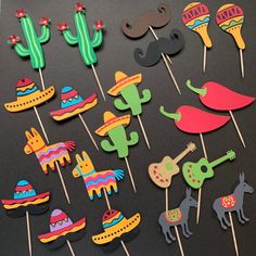 mexican themed cupcake toppers and picks on a black table with cactus, sombrero, guitar, mustaches