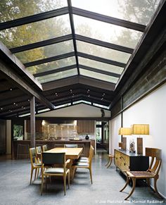 an open room with tables and chairs under a glass roof that is lit by lamps