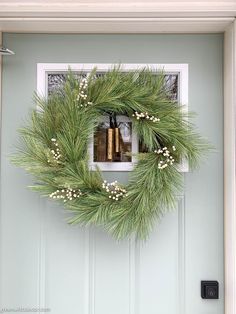 a wreath on the front door is decorated with white berries and greenery for christmas