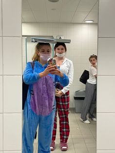 two women in pajamas and masks are taking a selfie