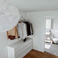 a white closet with clothes hanging on the wall