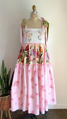 a dress on a mannequin next to a potted plant and a wooden chair