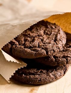 two chocolate cookies sitting on top of each other next to a piece of parchment paper