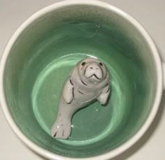 a white dog figurine in a green cup