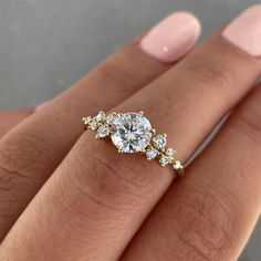 a woman's hand with an engagement ring on it, showing the center stone and side stones