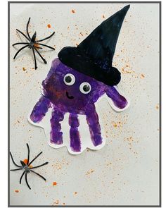 a hand with a witches hat on it and two spider's in the background