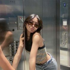 a woman leaning against a wall in front of a metal locker with buttons on it