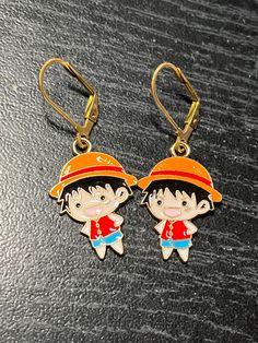 > DESCRIPTION < Enjoy your favorite stretchy man with these One Piece inspired earrings. The cute and colorful Luffy charm is golden alloy with colored enamel. They hang from stainless steel lever backs.  > SIZE < See images for measurements. Pay close attention to this detail so that there are no surprises in charm size.  > AMOUNT < Quantities may be more than what is listed. I may have more charms in stock to make additional designs if you need them for friends or family. Message or email me f Playful Gold Enamel Earrings, Themed Gold Earrings For Gifts, Fun Nickel-free Enamel Jewelry, Nickel-free Enamel Jewelry With Fun Style, Nickel-free Enamel Fun Jewelry, Playful Adjustable Gold Earrings, Gold Fun Drop Earrings, Fun Gold Drop Earrings, Playful Gold Drop Earrings Jewelry