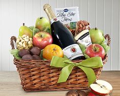 a basket filled with fruit and wine on top of a wooden table next to an apple